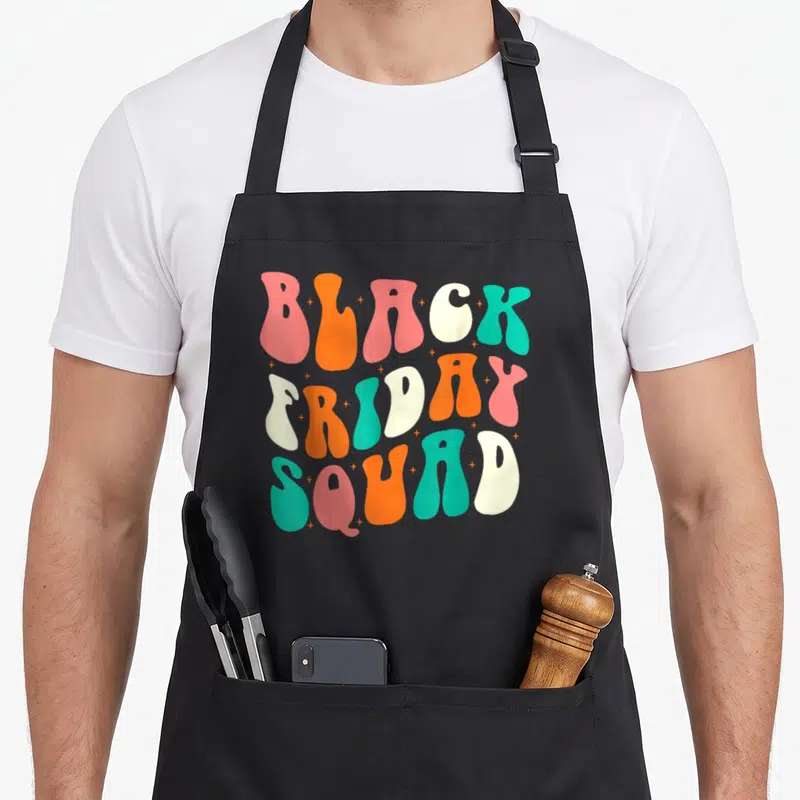 Groovy black friday apron - Bubbly text reading BLACK FRIDAY SQUAD in pink, orange, cream, and teal with small stars — shown on a black cotton canvas apron against a white background
