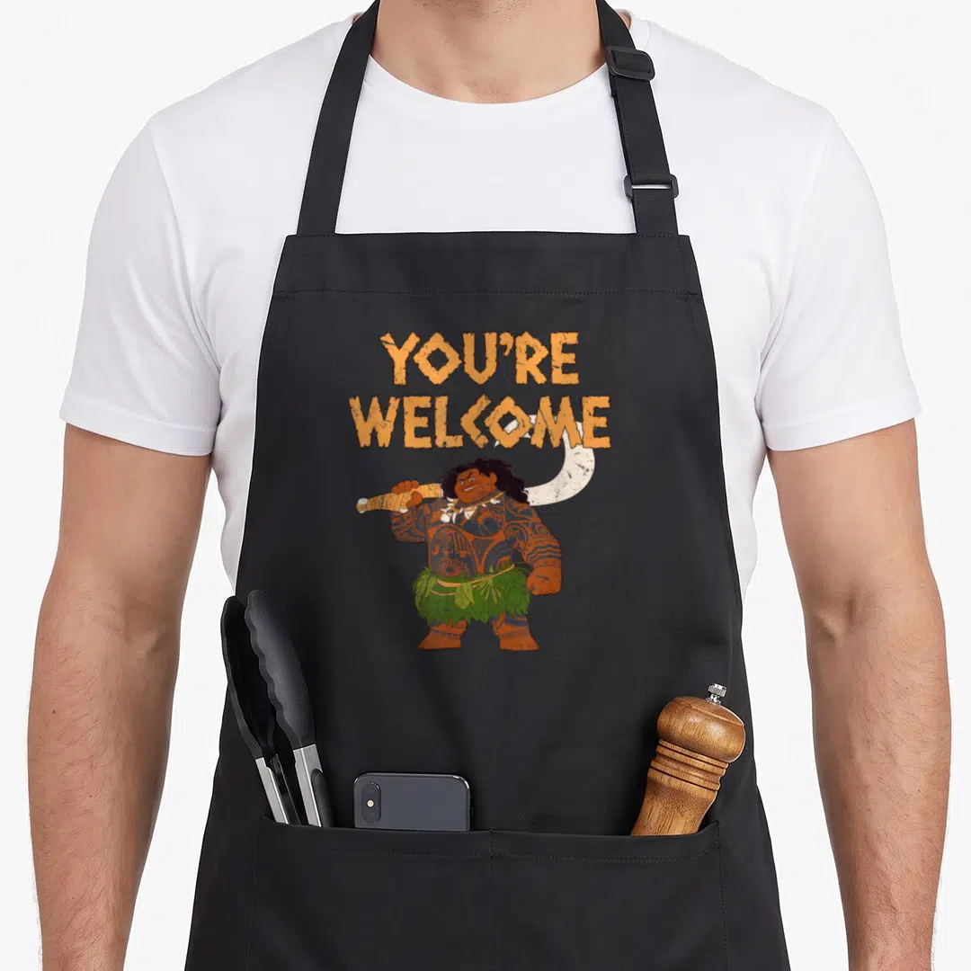 Confident novelty apron - You're Welcome text above cartoon character holding fishhook with green leaf skirt — shown on a black cotton canvas apron against a white background