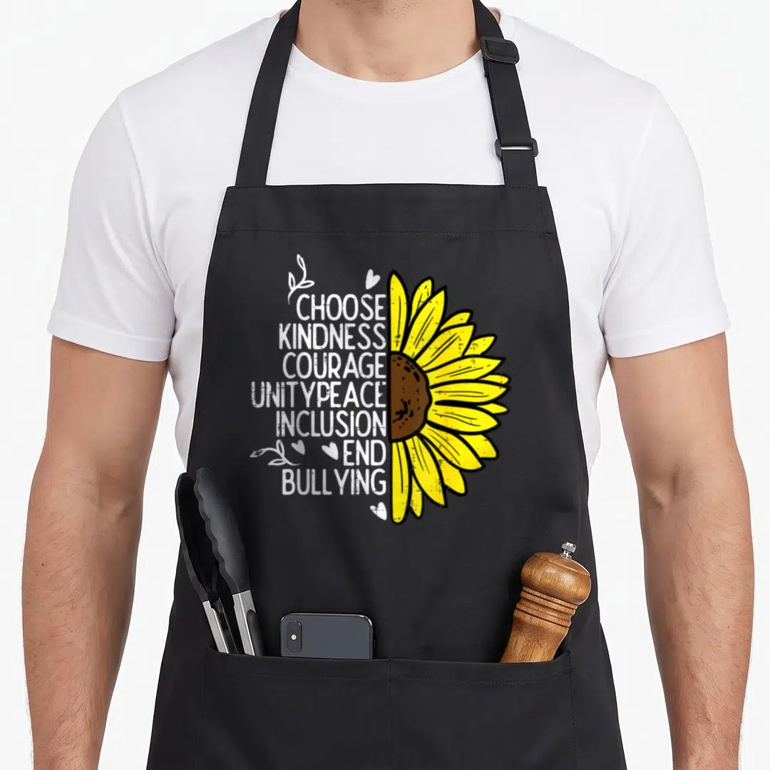 Kindness sunflower apron - Stacked text Choose Kindness End Bullying next to yellow sunflower half-circle — shown on a black cotton canvas apron against a white background