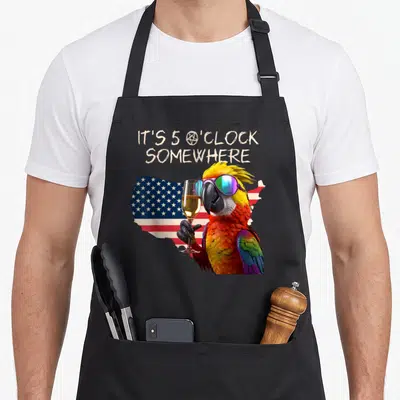 Grab toast apron - Parrot wearing sunglasses holding champagne glass in front of USA map flag with stacked text — shown on a black cotton canvas apron against a white background
