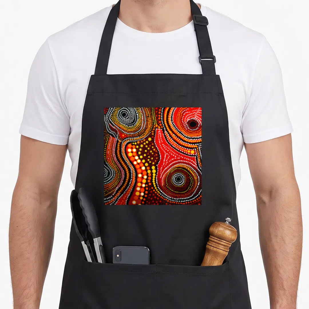 Painting australian apron - Abstract dot painting with red yellow white and black concentric circles on black background — shown on a black cotton canvas apron against a white background