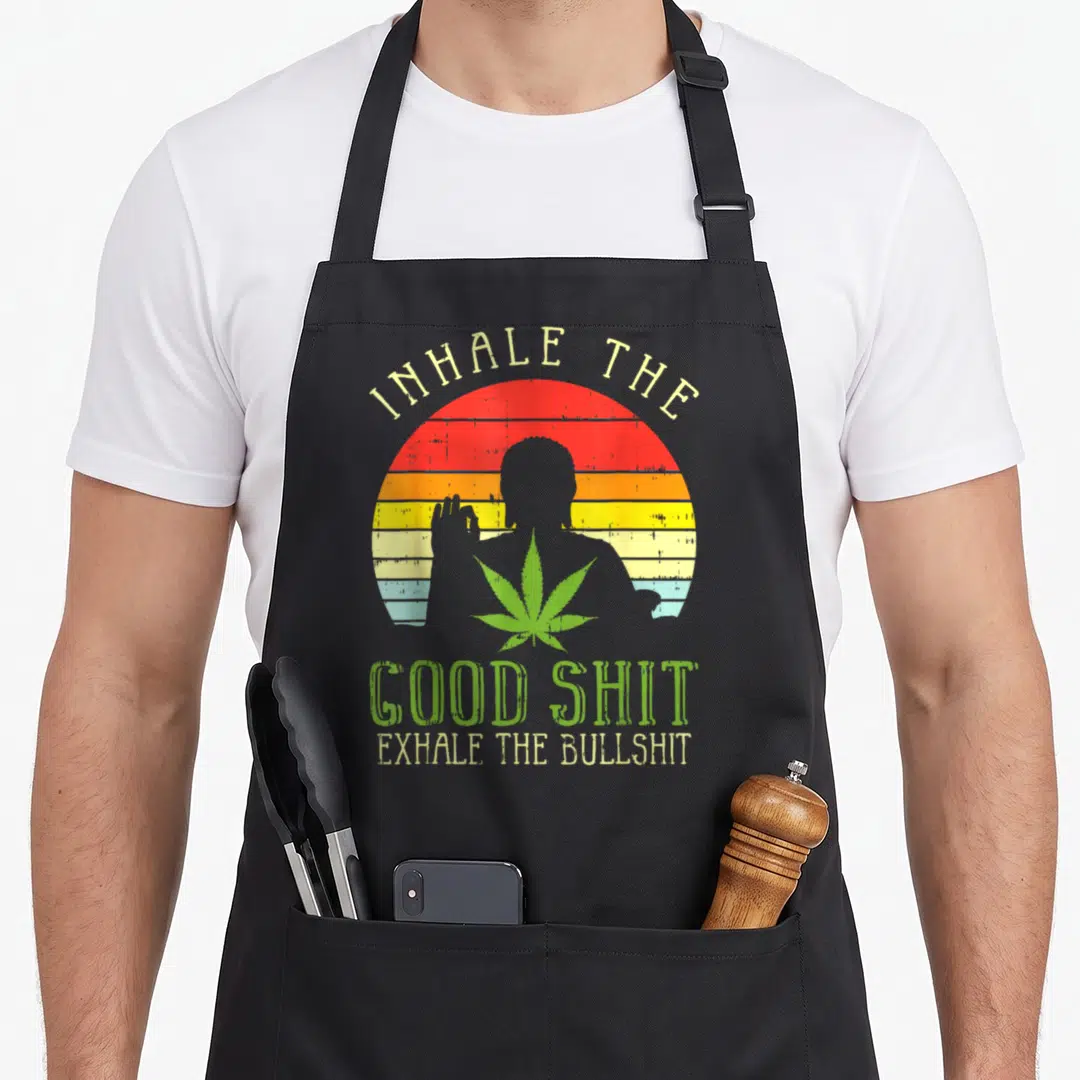 Inhale hemp apron - Retro sun stripes with person silhouette, green leaf, and inhale good shit exhale bullshit text — shown on a black cotton canvas apron against a white background
