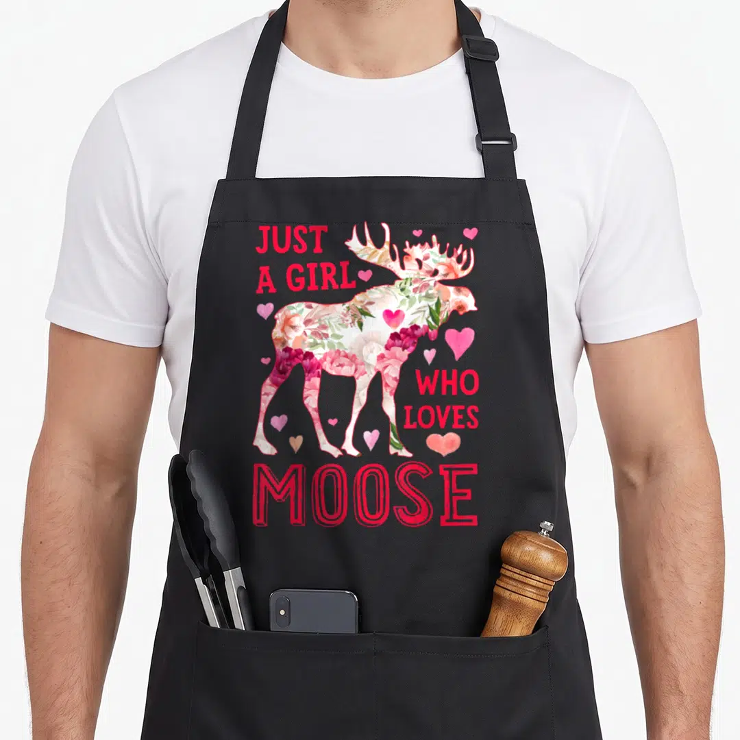 Moose floral apron - Floral-filled moose silhouette with scattered hearts and red text reading Just A Girl Who Loves — shown on a black cotton canvas apron against a white background