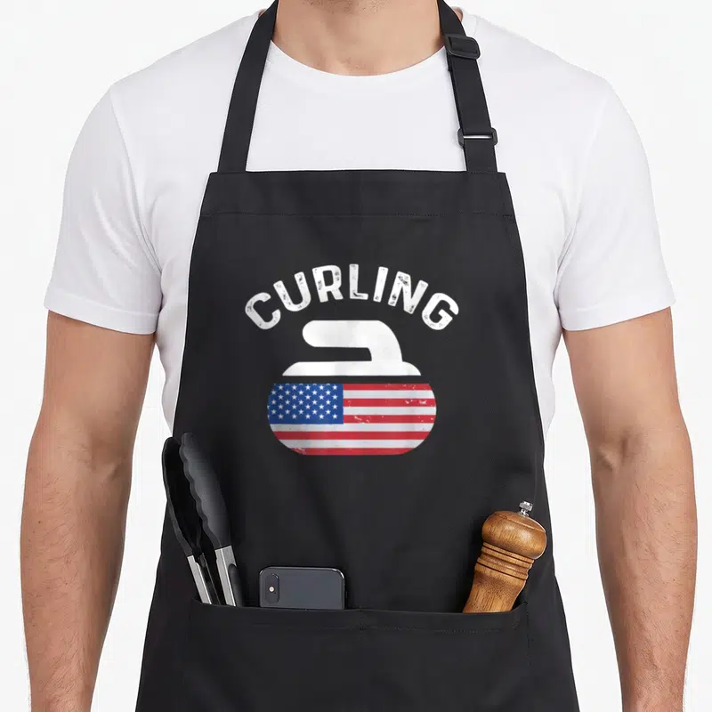 Curling american flag apron - Arched CURLING text above a stone graphic with red white blue flag pattern — shown on a black cotton canvas apron against a white background