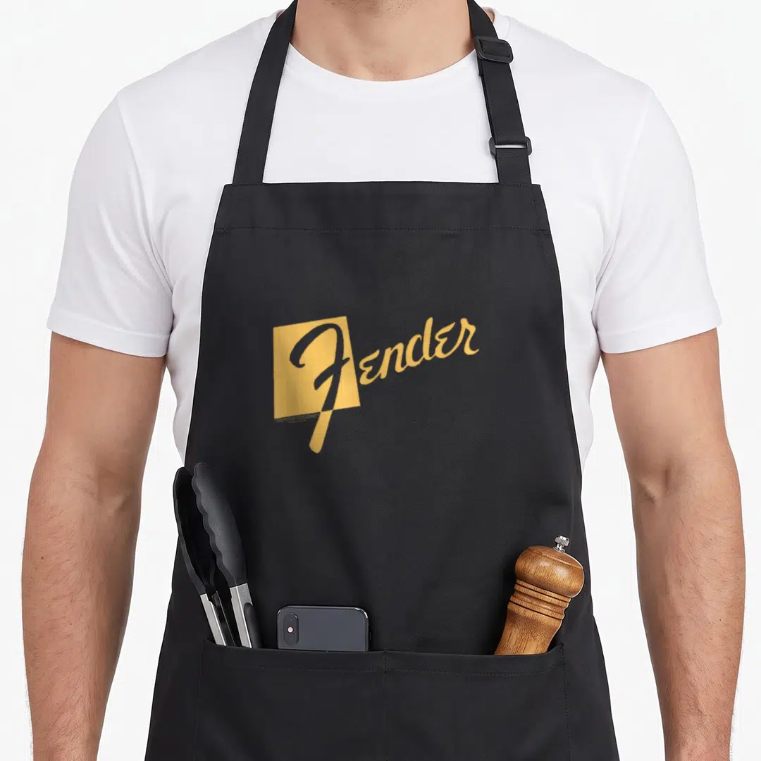 Funny fender apron - Gold Fender script text overlapping a gold rectangle on black fabric — shown on a black cotton canvas apron against a white background