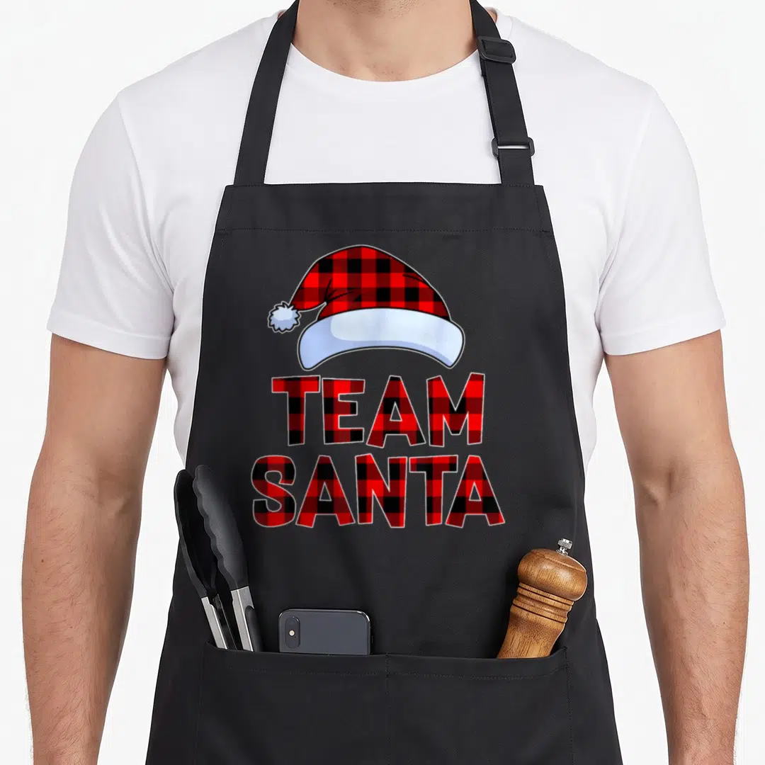 Plaid santa aprons - Red black plaid Santa hat above stacked TEAM SANTA text in cartoon style — shown on a black cotton canvas apron against a white background