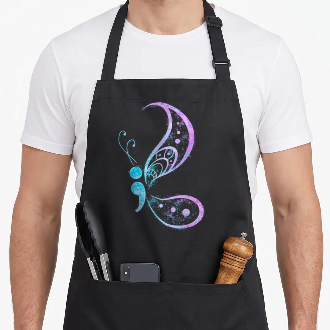 Semicolon tattoo apron - Purple blue cyan watercolor butterfly shaped like a semicolon — shown on a black cotton canvas apron against a white background