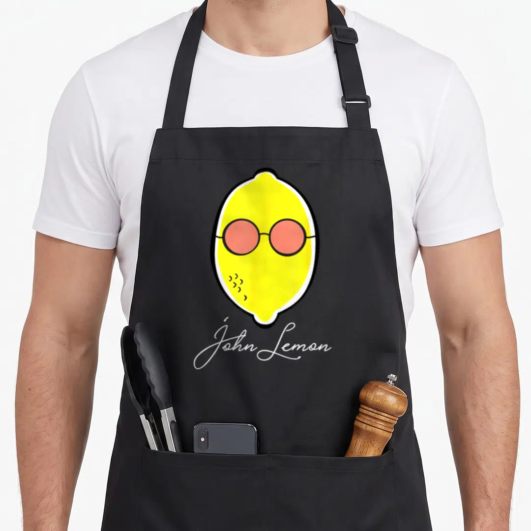 John lemon apron - Yellow cartoon lemon wearing pink round glasses above white John Lemon script text — shown on a black cotton canvas apron against a white background