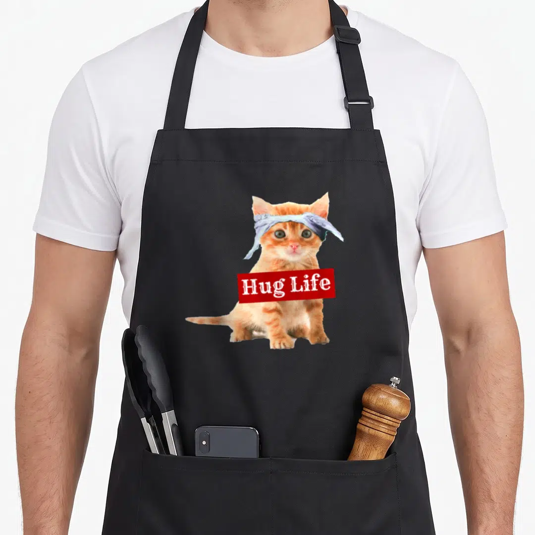 Hug kitty cat apron - Orange kitten with blue bandana and red box reading Hug Life — shown on a black cotton canvas apron against a white background