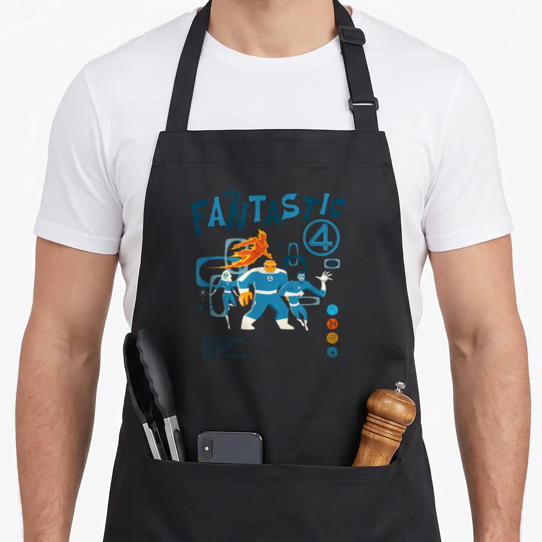 Heroe first steps apron - Retro Fantastic Four print with THE FANTASTIC 4 title and character names in blue orange white — shown on a black cotton canvas apron against a white background