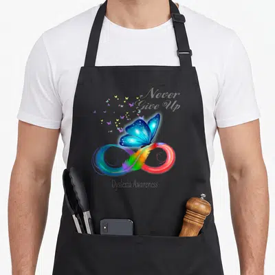 Dyslexia butterfly apron - Blue butterfly on rainbow infinity symbol with feather and text Never Give Up Dyslexia — shown on a black cotton canvas apron against a white background