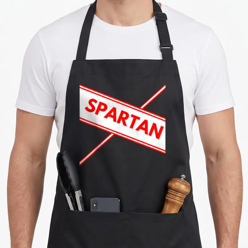 Spartan easy apron - Red and white ribbon with SPARTAN text in block letters — shown on a black cotton canvas apron against a white background