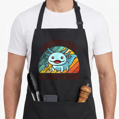 Axolotl question apron - Cartoon blue axolotl on striped sun with I AXOLOTL QUESTIONS text — shown on a black cotton canvas apron against a white background