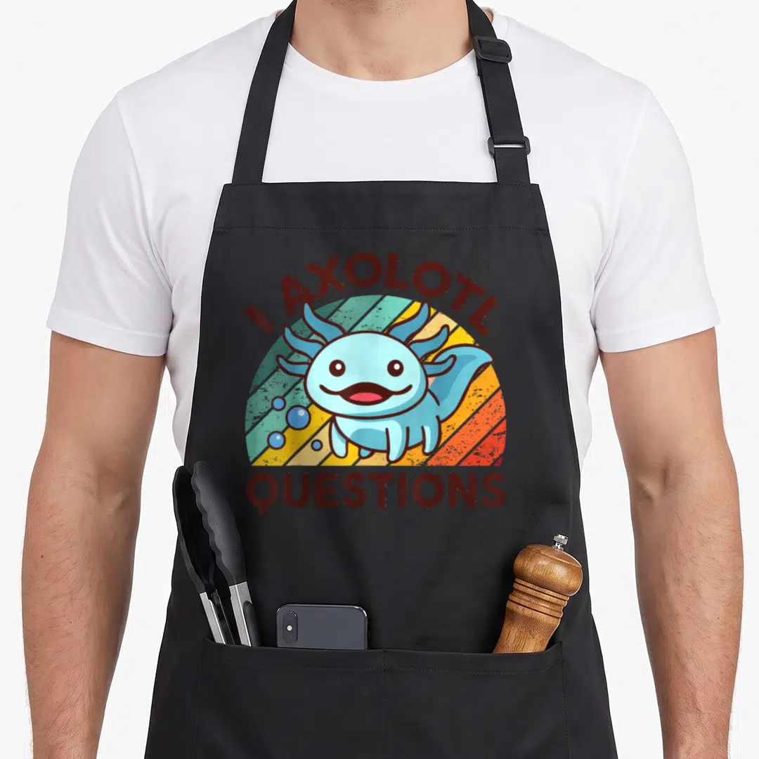 Axolotl question apron - Cartoon blue axolotl on striped sun with I AXOLOTL QUESTIONS text — shown on a black cotton canvas apron against a white background