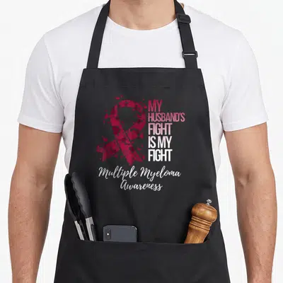 Fight husband apron - Heart ribbon and text My Husband's Fight Is My Fight Multiple Myeloma Awareness — shown on a black cotton canvas apron against a white background
