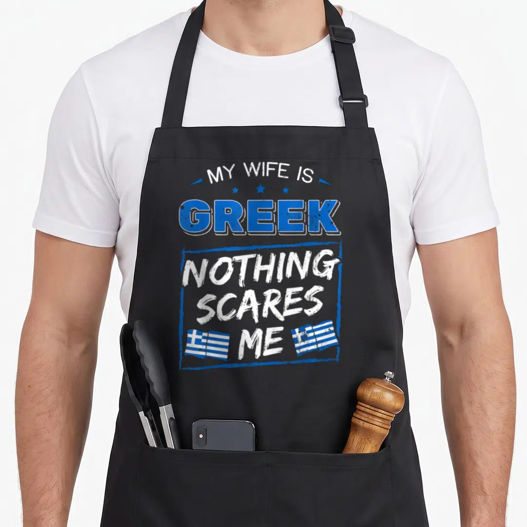 Greek wife apron - Stacked blue and white text My Wife Is Greek Nothing Scares Me with three stars and two Greek flags — shown on a black cotton canvas apron against a white background