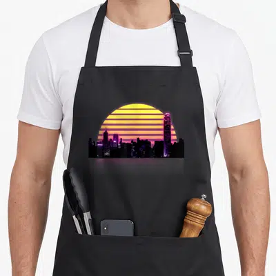 Synthwave retrowave 80s apron - Purple city skyline silhouette against a striped yellow and orange sun in retro style — shown on a black cotton canvas apron against a white background