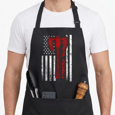 Til patriotic apron - Red ornate battle axe over distressed white US flag with vertical TIL VALHALLA text — shown on a black cotton canvas apron against a white background