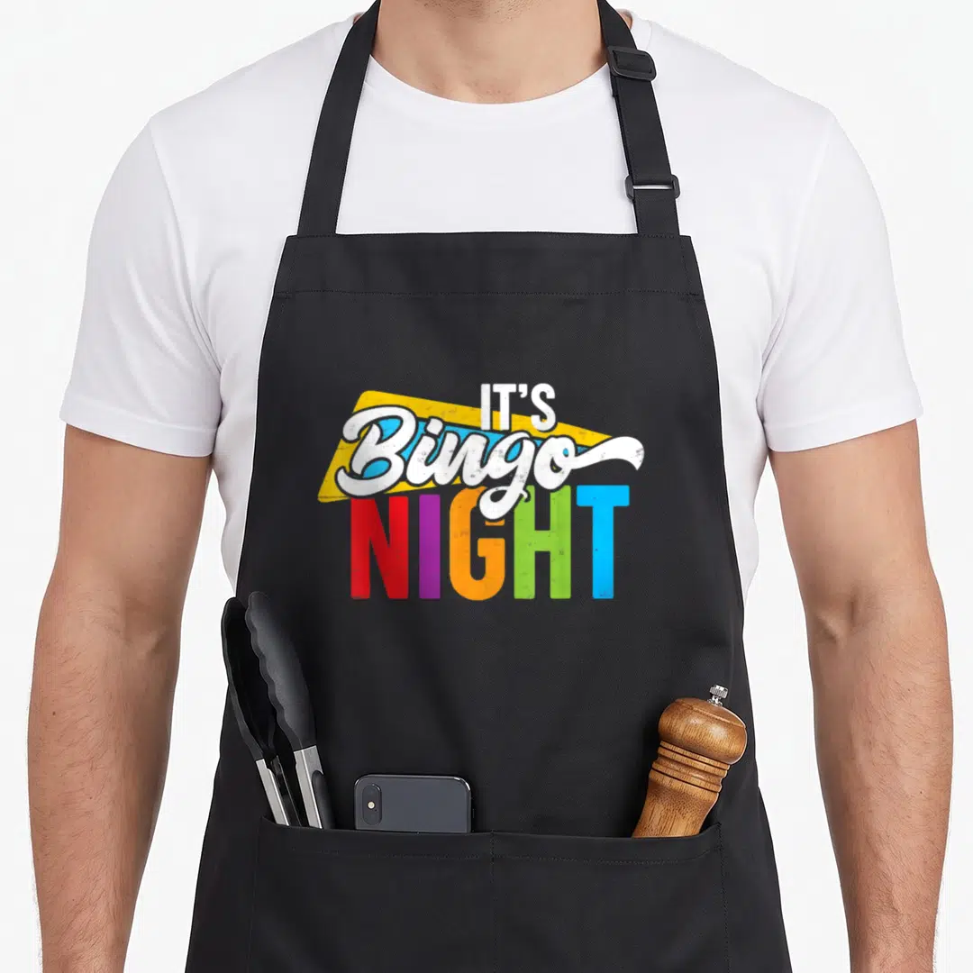 Night player bingo apron - Stacked IT'S Bingo NIGHT text with yellow triangle and rainbow colored letters — shown on a black cotton canvas apron against a white background
