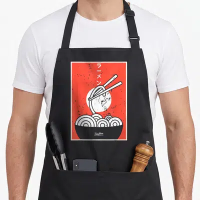 Ramen thai girl apron - Red background with grey ramen bowl, white sun, chopsticks lifting noodles, vertical Japanese — shown on a black cotton canvas apron against a white background