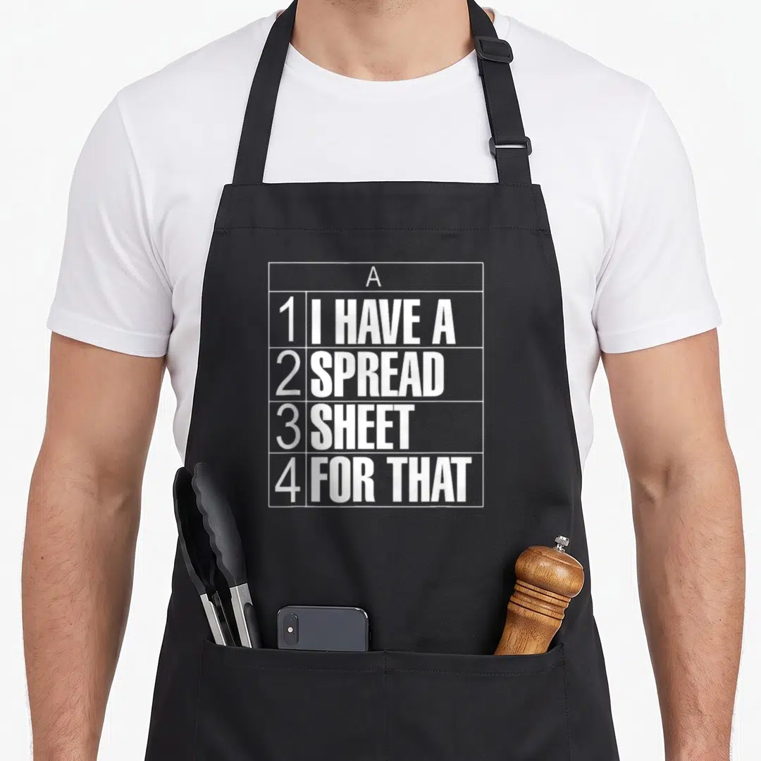 Spreadsheet tax apron - White grid containing text I HAVE A SPREAD SHEET FOR THAT arranged in rows 1 through 4 — shown on a black cotton canvas apron against a white background