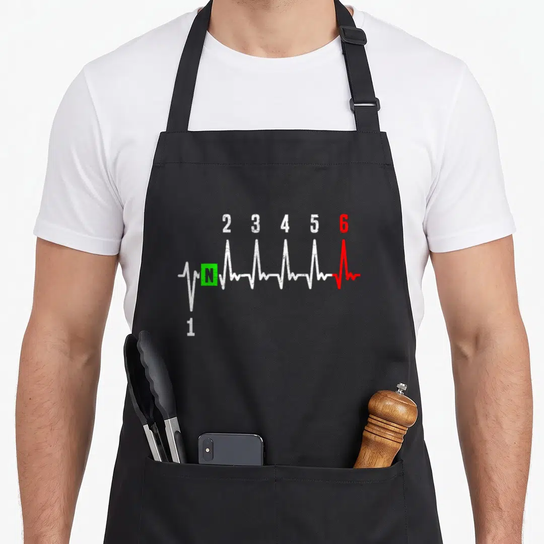 1n23456 motorcycle apron - Distressed gear shift numbers 1-6 and N on a heartbeat line in white red and green — shown on a black cotton canvas apron against a white background