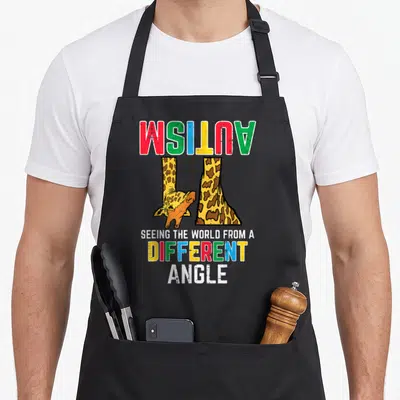 Autism giraffe apron - Upside down giraffe with inverted rainbow text reading autism and seeing the world — shown on a black cotton canvas apron against a white background
