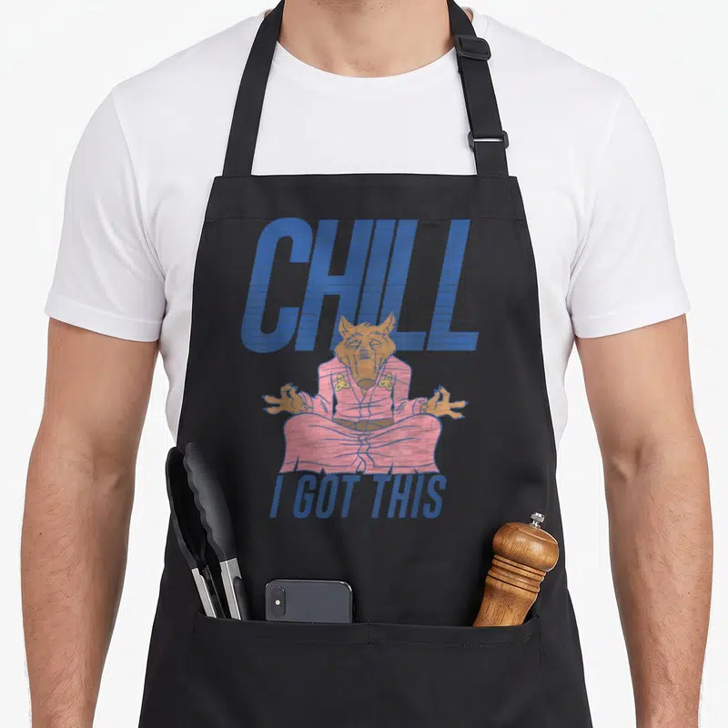Chill master apron - Meditating wolf in pink robe with blue CHILL I GOT THIS text — shown on a black cotton canvas apron against a white background