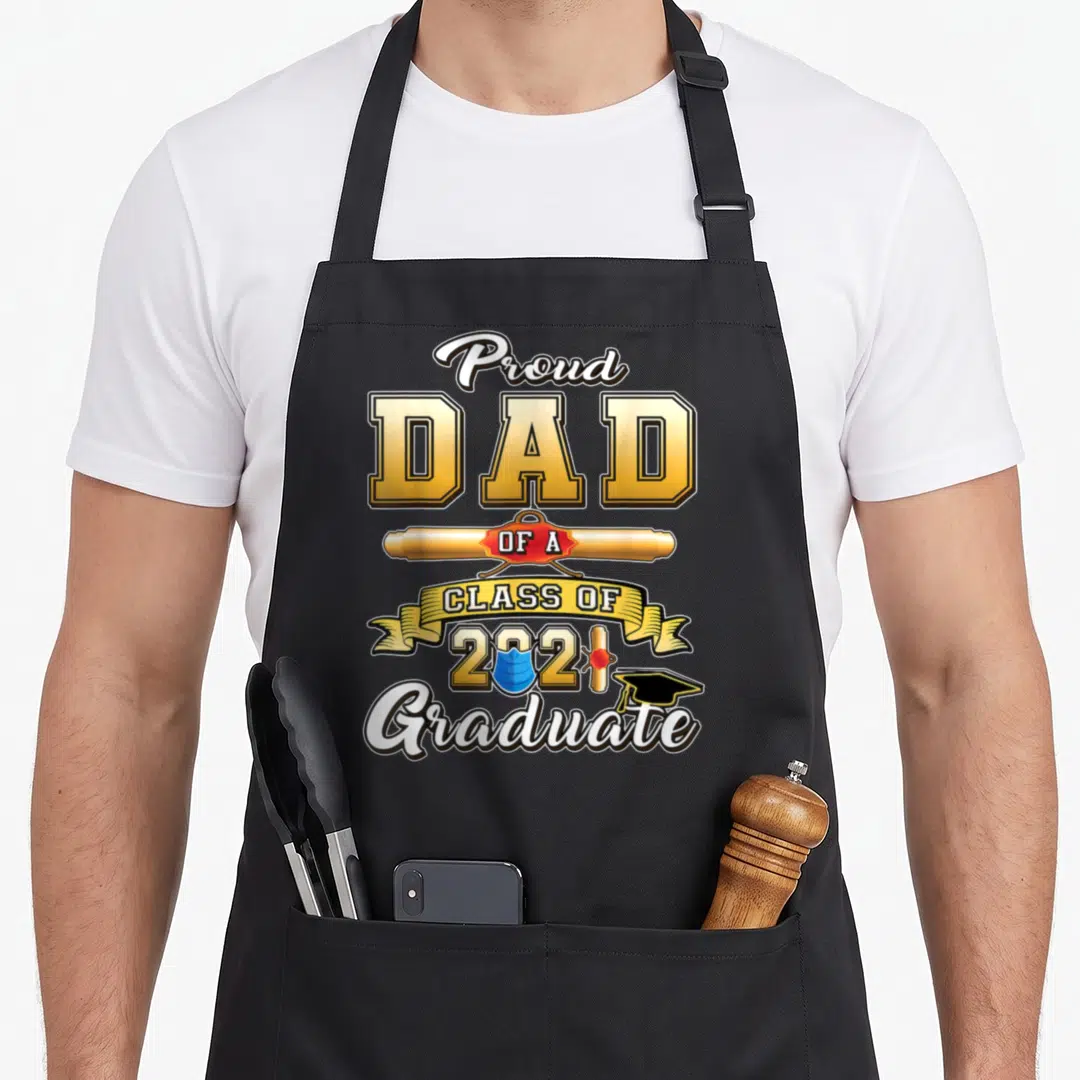 Graduate dad class apron - Proud Dad Class of 2021 Graduate text with diploma and face mask icon in yellow and black — shown on a black cotton canvas apron against a white background