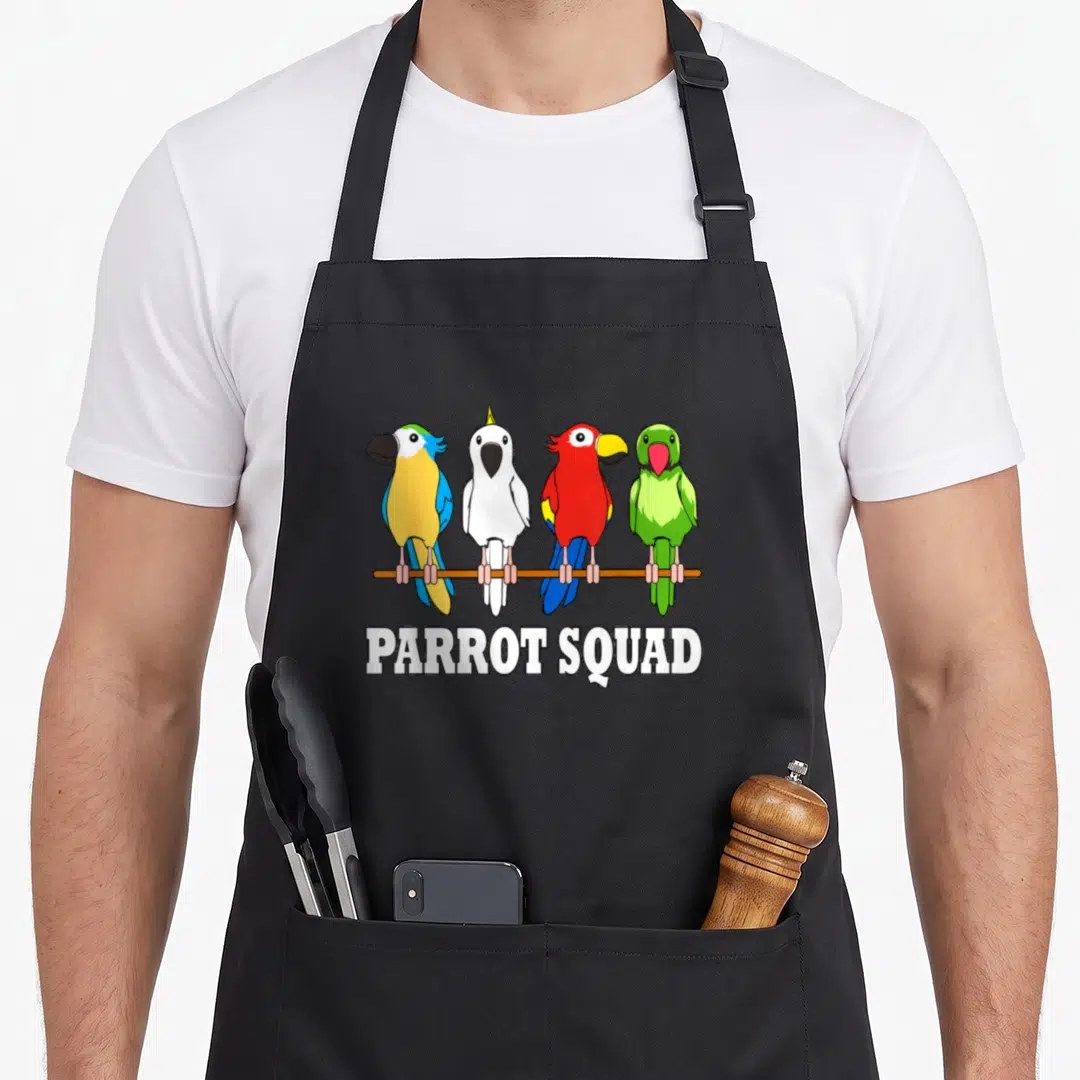 Squad bird apron - Four cartoon parrots on a branch with PARROT SQUAD text below — shown on a black cotton canvas apron against a white background