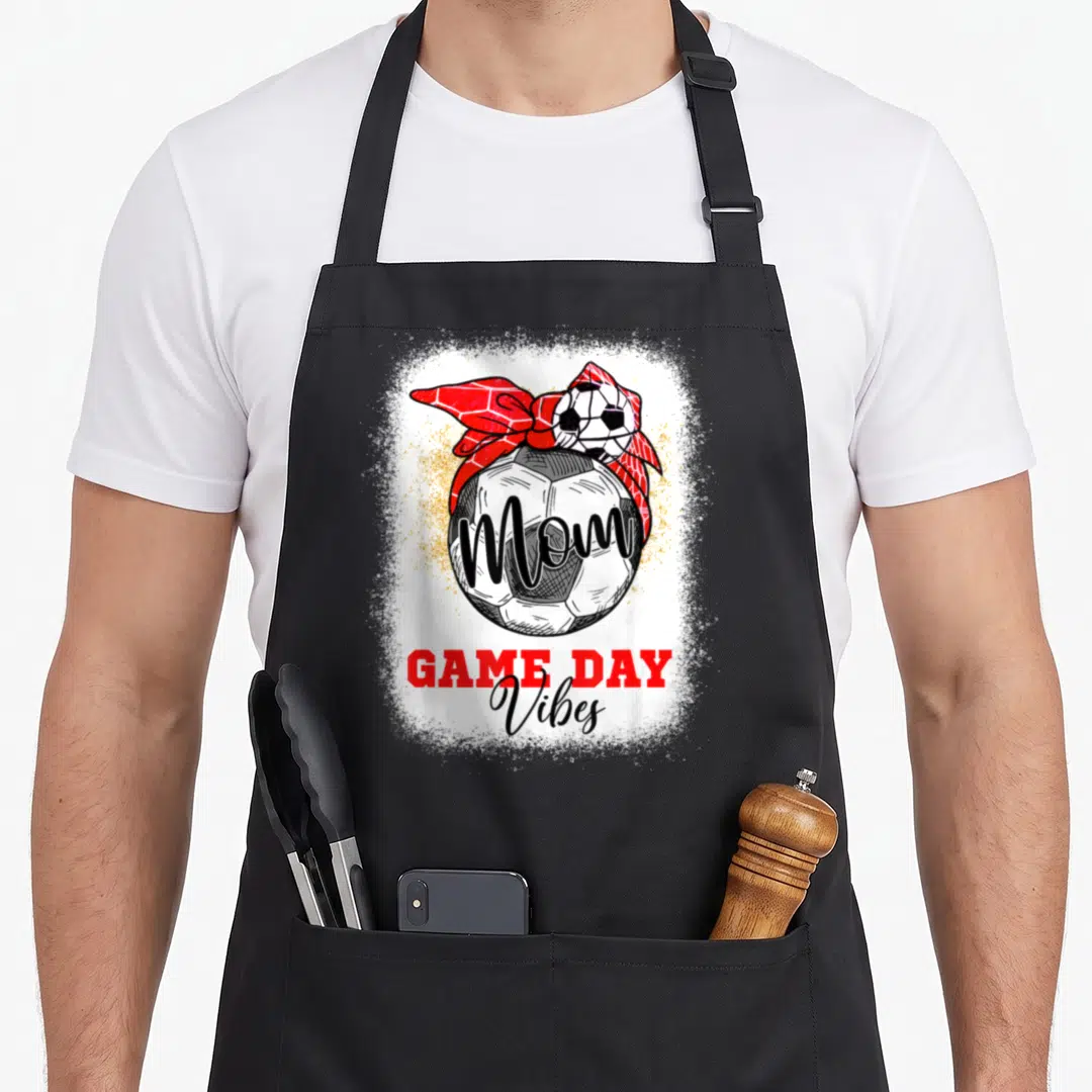 Soccer game mother's day aprons - Soccer ball with red bandana and Mom text on gold splatter background — shown on a black cotton canvas apron against a white background