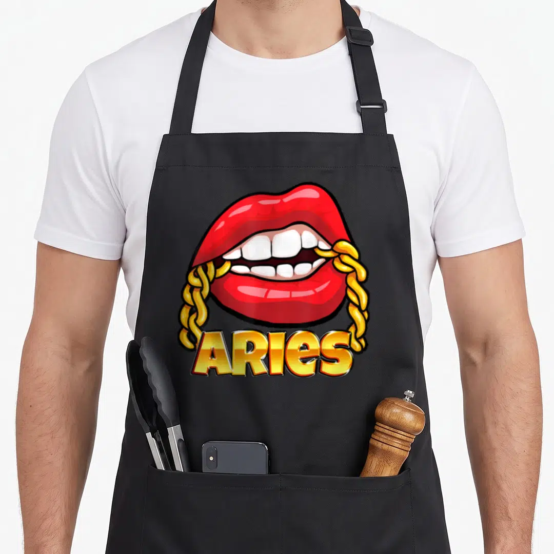 Necklace zodiac aprons - Red cartoon lips holding gold chain with ARIES text below — shown on a black cotton canvas apron against a white background