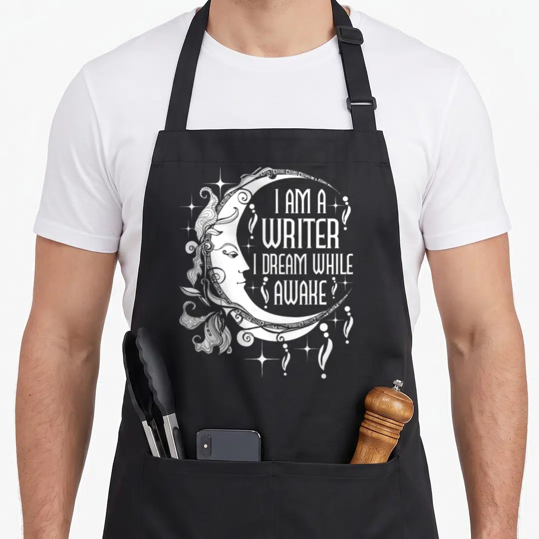 Writer poet apron - White crescent moon containing stacked text I Am A Writer I Dream While Awake surrounded by stars — shown on a black cotton canvas apron against a white background