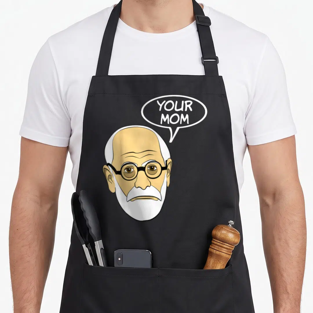 Psychoanalysis geek apron - Cartoon bald man with glasses and white beard saying YOUR MOM in speech bubble — shown on a black cotton canvas apron against a white background