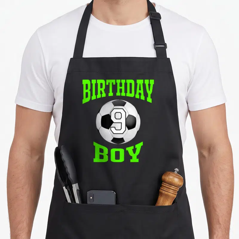 Funny 9th birthday apron - Soccer ball with number 9 flanked by lime green BIRTHDAY BOY text — shown on a black cotton canvas apron against a white background