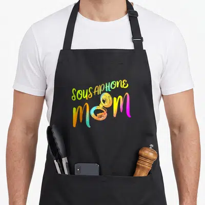Member tuba apron - Colorful SOUSAPHONE MOM text with brass instrument replacing the O in Mom — shown on a black cotton canvas apron against a white background