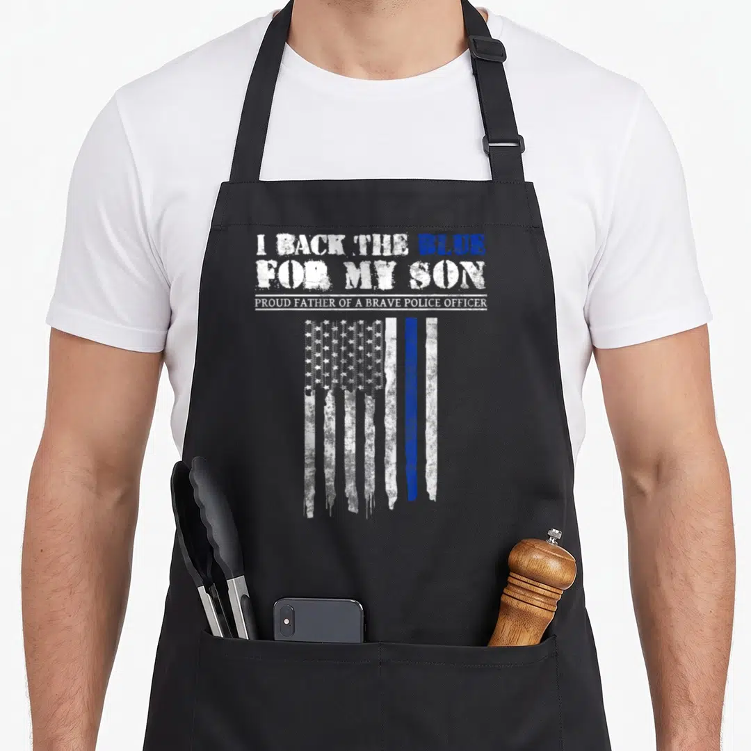 Police dad and son aprons - Distressed white and blue flag with I BACK THE BLUE FOR MY SON text — shown on a black cotton canvas apron against a white background