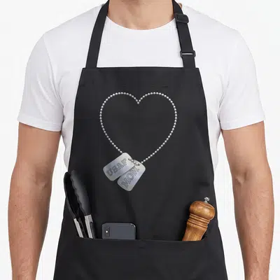 Tag dog apron - Realistic silver dog tags reading USAF and MOM on a heart-shaped chain — shown on a black cotton canvas apron against a white background