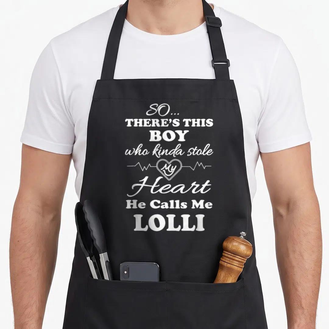 Stole lollipop apron - White stacked text with heartbeat line reading So There's This Boy Who Kinda Stole My Heart He — shown on a black cotton canvas apron against a white background