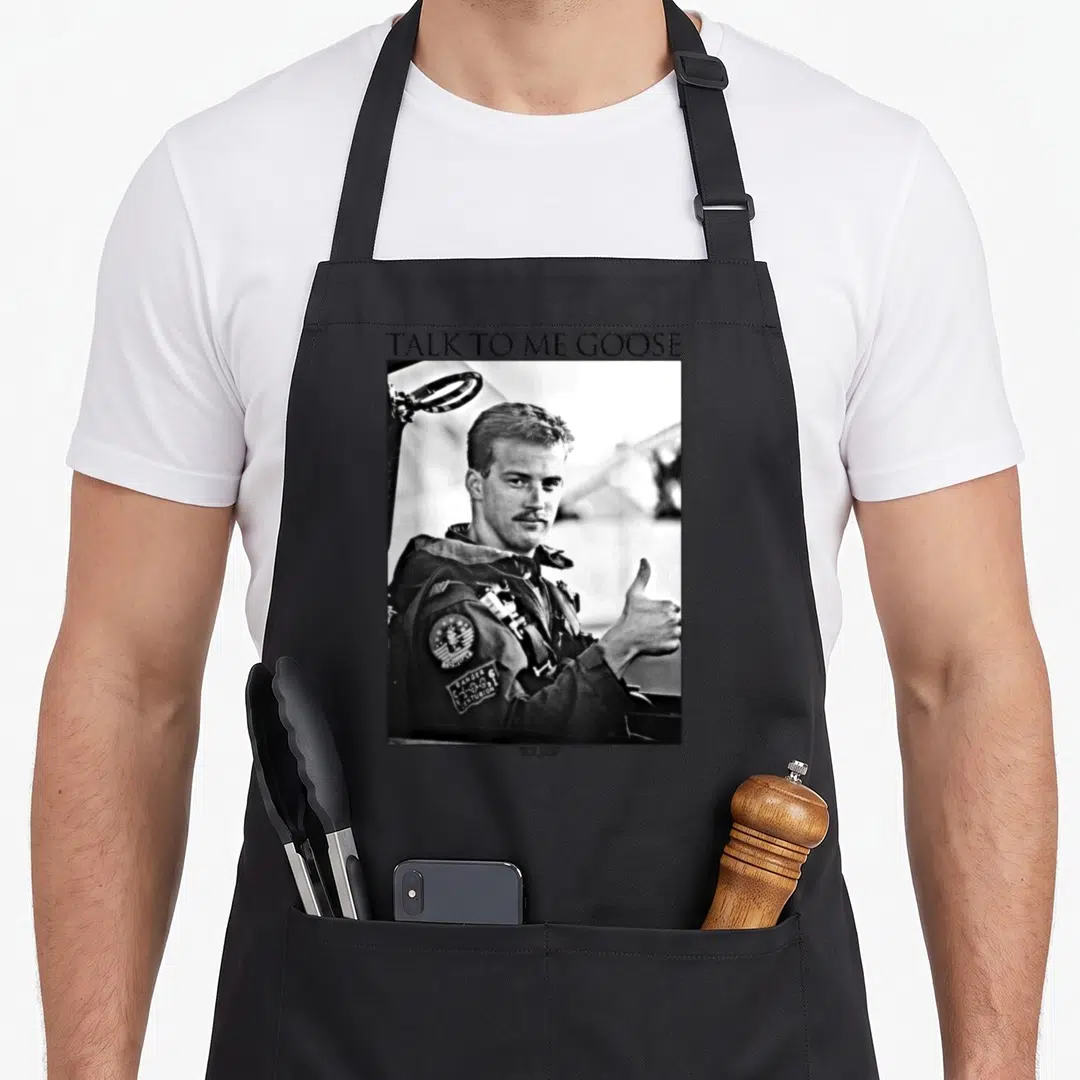 Talk goose apron - TALK TO ME GOOSE text above grayscale photo of man giving thumbs up — shown on a black cotton canvas apron against a white background