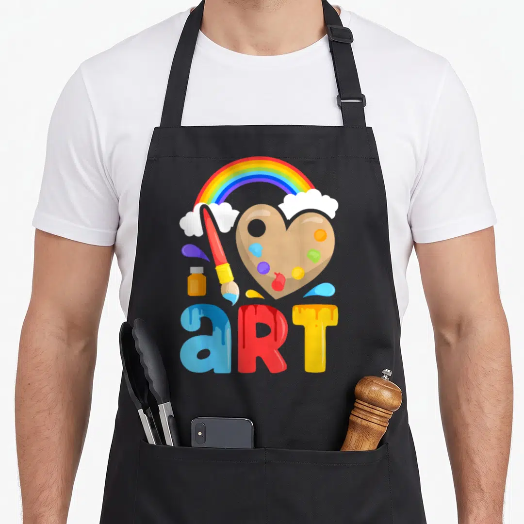 Colorful painter apron - Rainbow, heart palette, paintbrush, and dripping art text in red yellow blue orange — shown on a black cotton canvas apron against a white background