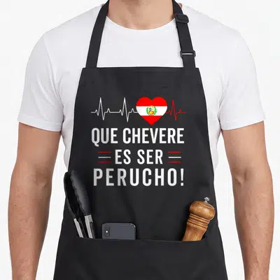 Perucho pride apron - Que Chevere Es Ser Perucho text below red white heartbeat heart with flag pattern — shown on a black cotton canvas apron against a white background