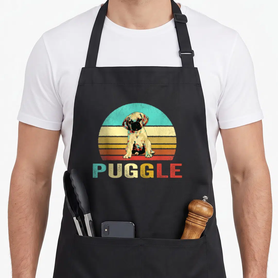 Puggle dog apron - Retro seated pug in front of blue yellow orange red tan striped semi-circle with PUGGLE text below — shown on a black cotton canvas apron against a white background