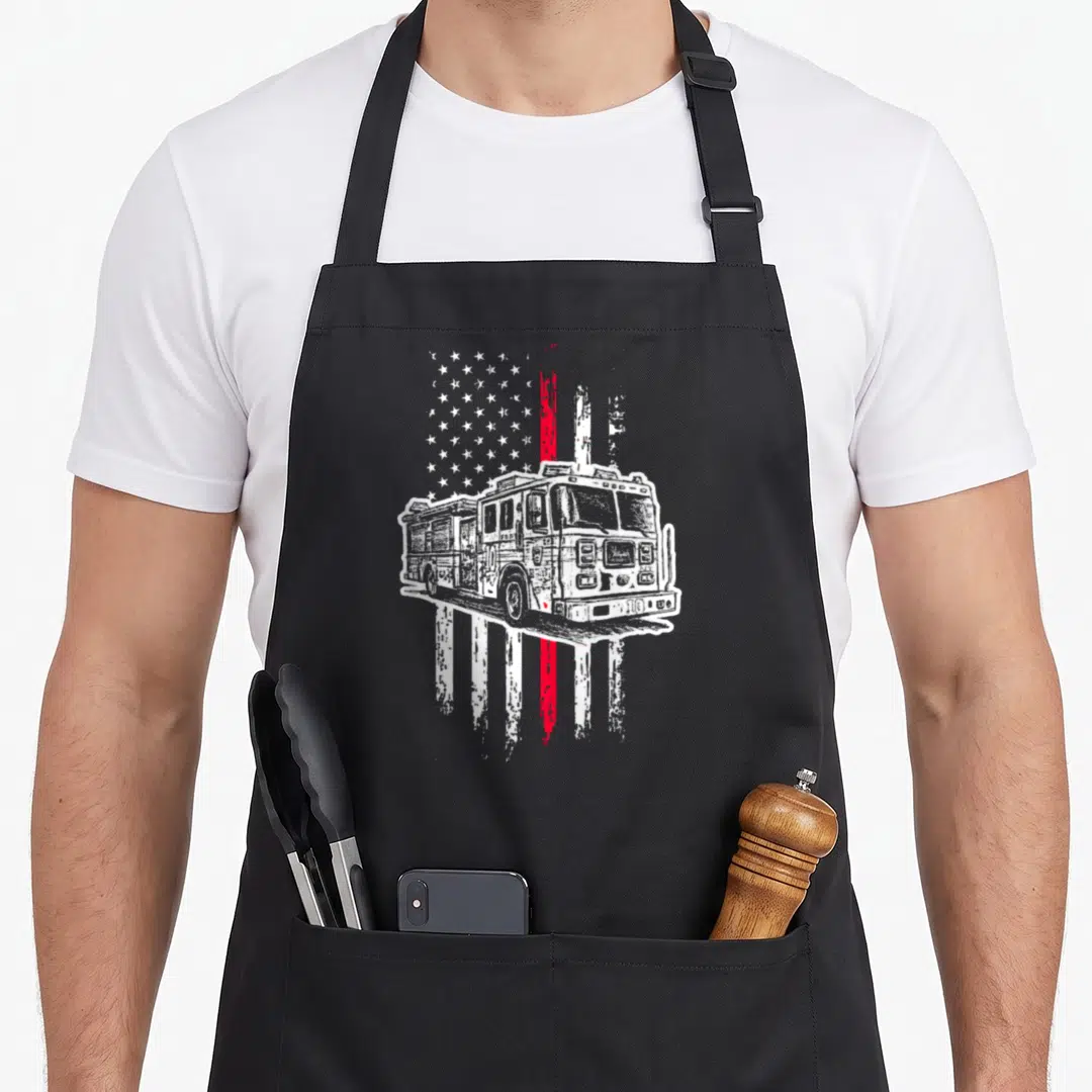Fireman line apron - White fire truck over distressed flag with single vertical red stripe — shown on a black cotton canvas apron against a white background