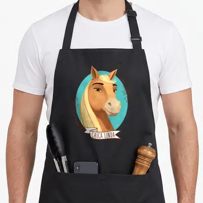 Chica novelty apron - Tan horse head with blonde mane in turquoise circle, brown leaf sprigs, white ribbon with text — shown on a black cotton canvas apron against a white background