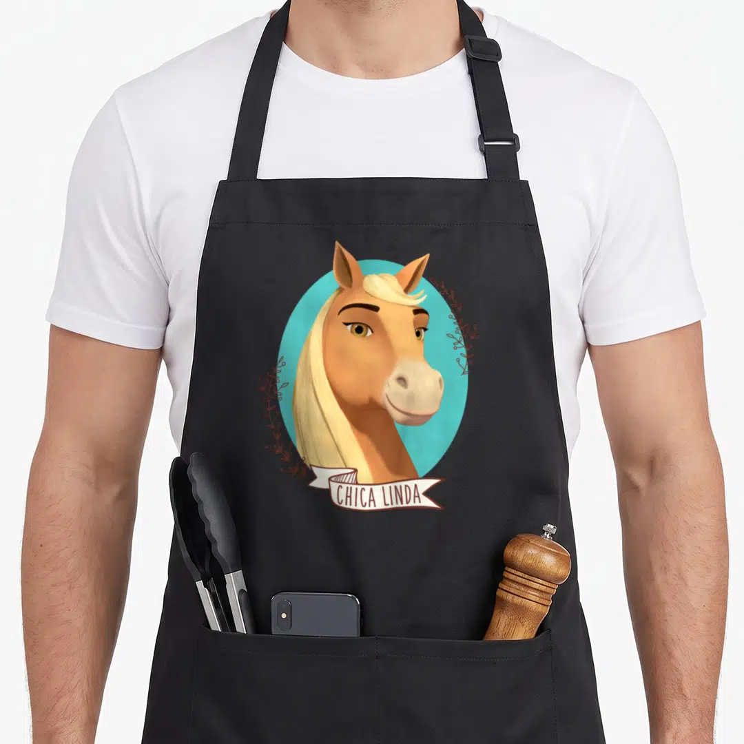 Chica novelty apron - Tan horse head with blonde mane in turquoise circle, brown leaf sprigs, white ribbon with text — shown on a black cotton canvas apron against a white background