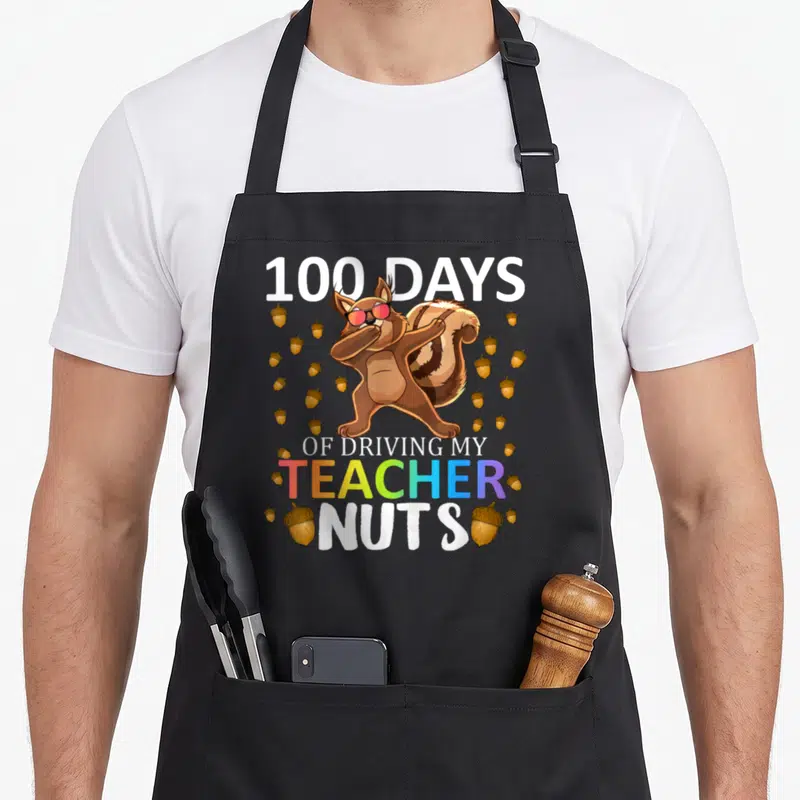 Driving teacher apron - Dabbing squirrel with sunglasses and 100 Days Of Driving My Teacher Nuts text surrounded — shown on a black cotton canvas apron against a white background