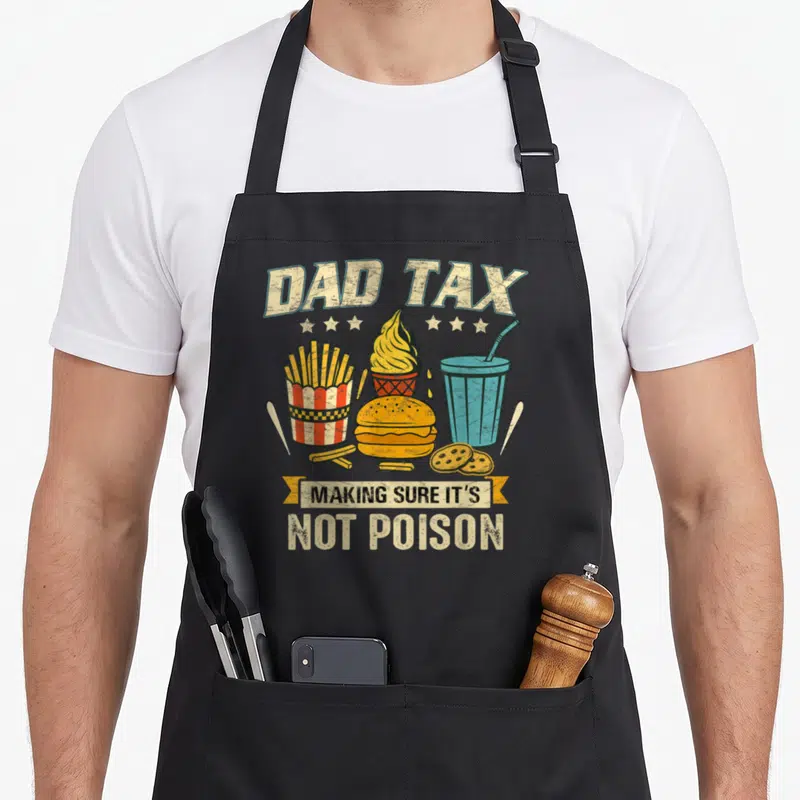 Tax sure making an apron - DAD TAX MAKING SURE IT'S NOT POISON fast food cartoon print on black bib — shown on a black cotton canvas apron against a white background