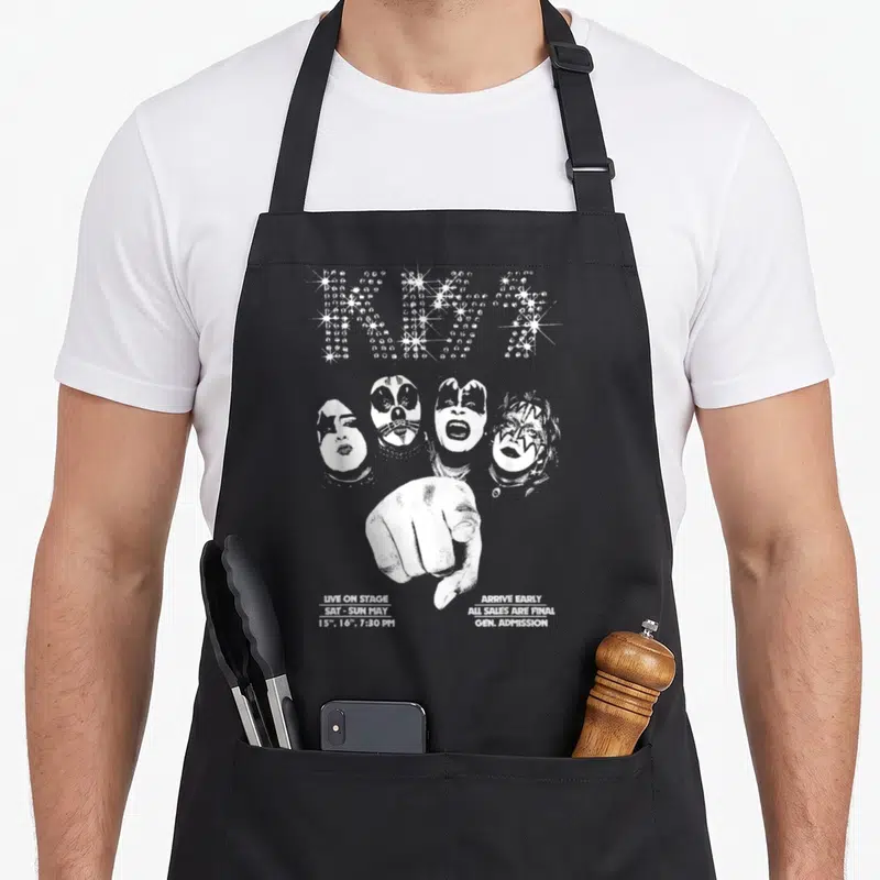 Funny kiss kissimmee apron - Distressed white KISS star logo, four band faces, pointing hand, and concert date text — shown on a black cotton canvas apron against a white background