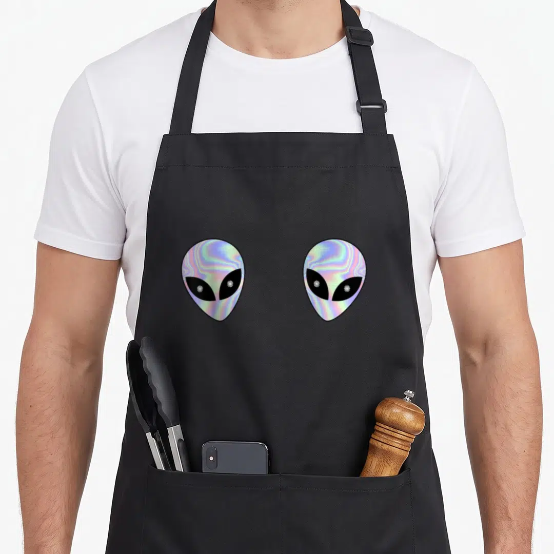 Rave colorful aprons - Two holographic alien heads in blue purple pink and black — shown on a black cotton canvas apron against a white background